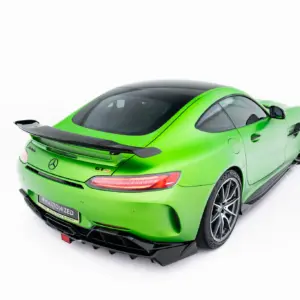 Rear three-quarter view of a bright green Mercedes sports car with a large spoiler and black roof on a white background.