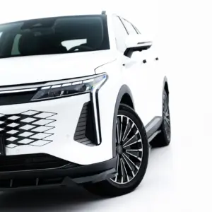 Front-left view of a white SUV showing the grille, headlight, and large alloy wheel with the #MAXTONIZED plate visible on the bumper.