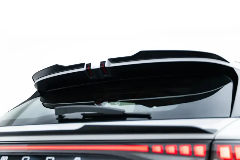 Close-up of a white car's rear with an elevated spoiler and red taillights glowing at the edge of the trunk area
