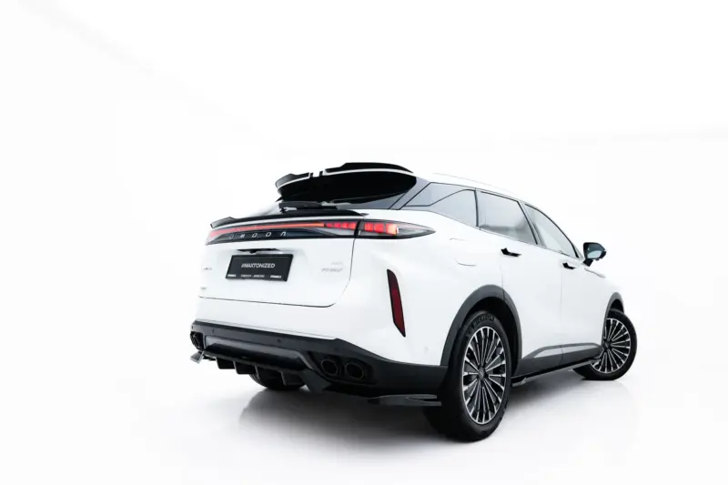 Rear three-quarter view of a white SUV with a black roof rack on a white studio backdrop, showing distinctive tail lights and large alloy wheels.