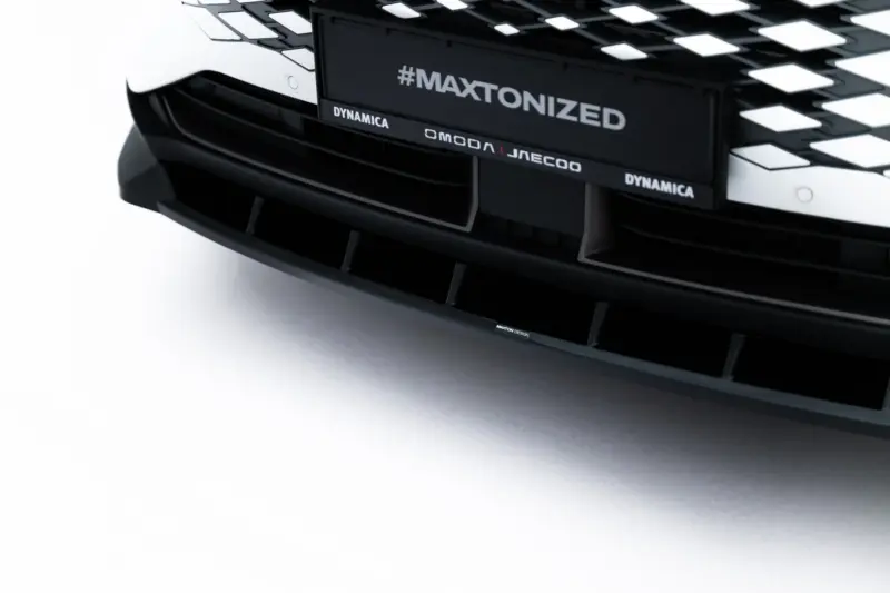 Close-up of a black car front showing the grille with the hashtag '#MAXTONIZED' and branding text, including 'DYNAMICA'.