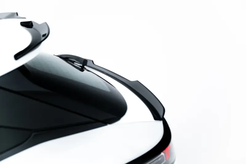 Close-up of a white car's rear end with glossy black trim and red taillight, viewed from a low angle against a white background.
