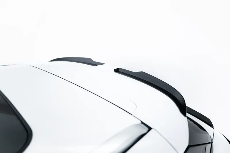 Close-up of a white car roof with a black spoiler and window trim against a pale background.