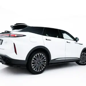 Rear-side view of a white SUV with a black roof cargo box and stylish alloy wheels, set against a bright background.