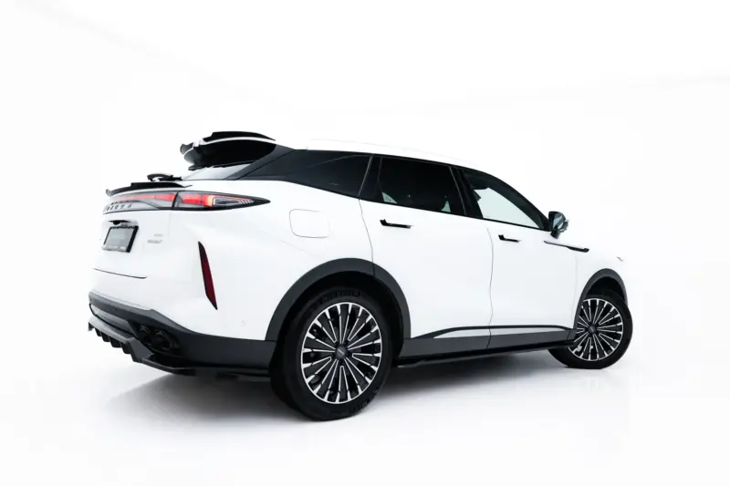 Rear-side view of a white SUV with a black roof cargo box and stylish alloy wheels, set against a bright background.
