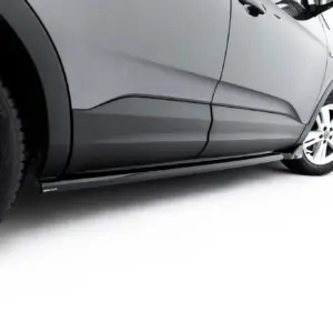 Close-up of a silver SUV side panel and front wheel with white background behind it