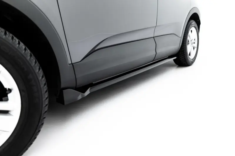 Close-up of a gray car's side panel and front wheel, showing body lines and tire tread
