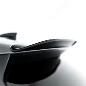 Close-up of a sleek car exterior, showing a chrome trim and curved window against a white background.
