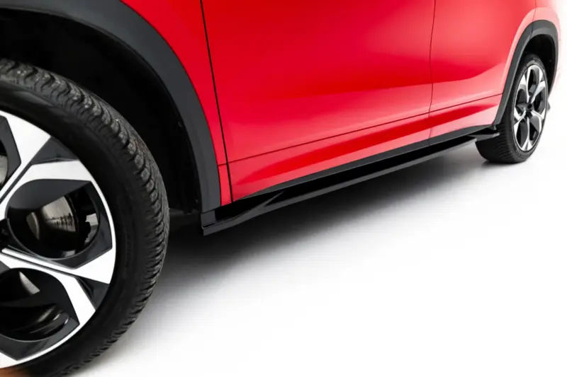Close-up of a red car body with a visible alloy wheel and tire, highlighting glossy paint and curves.
