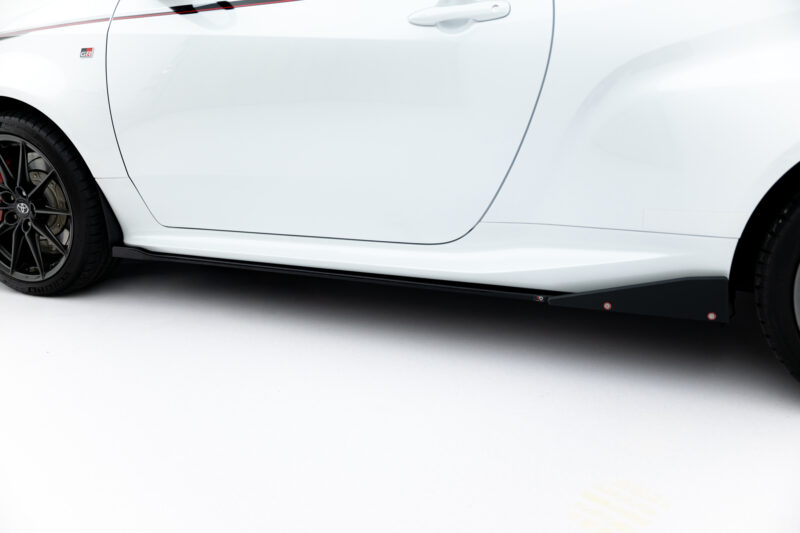 Close-up of a white car's side panel and wheel, showing the door, seam, and black alloy wheel with brake caliper visible on the left edge.