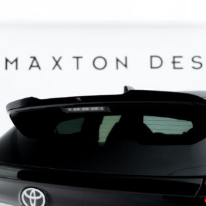 Rear view of a dark SUV with a black spoiler, Toyota badge, and a blurred 'MAXTON DESIGN' sign in the bright background.