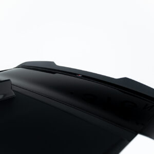 Close-up of a glossy black car roof with a small red-and-white badge against a white background.