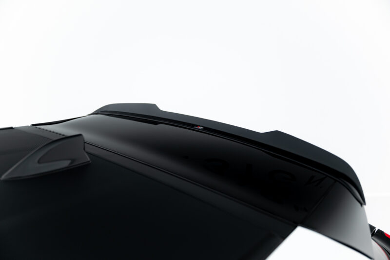 Close-up of a glossy black car roof with a small red-and-white badge against a white background.