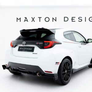 Rear view of a white Toyota GR Yaris in a studio with a large 'MAXTON DESIGN' sign on the wall behind.