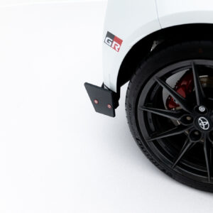 Close-up of a white car wheel with a black alloy rim, red brake caliper, and a GR badge on the fender.