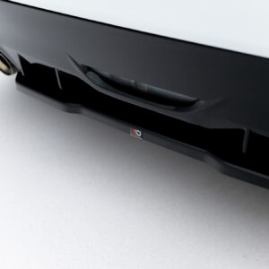 Close-up of a glossy black car bumper with a small Maxton Design logo visible on the lower edge.