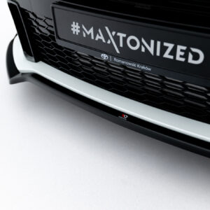 Close-up of a black car front showing a hexagonal grille and a license plate reading '#MAXTONIZED'.