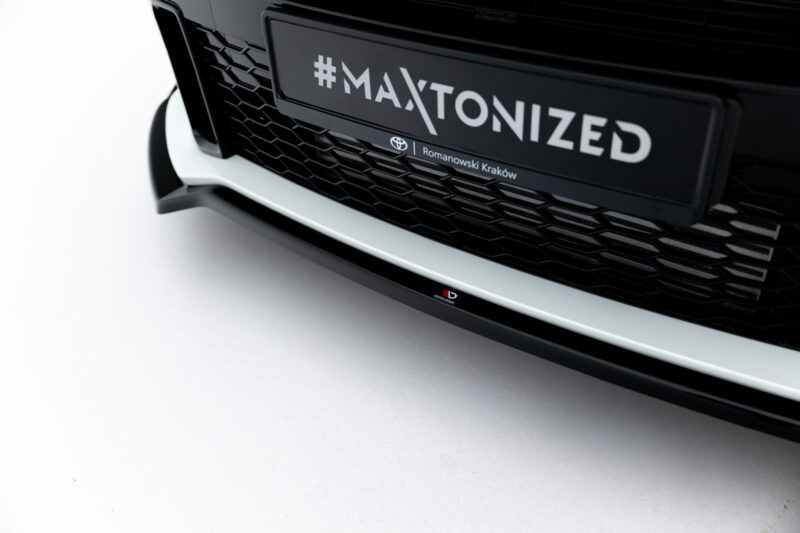 Close-up of a black car front showing a hexagonal grille and a license plate reading '#MAXTONIZED'.