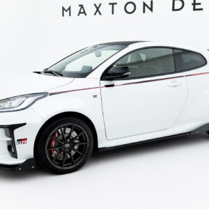 Side-front view of a white sports hatchback with black roof, red racing stripe, black wheels, and GR badges, photographed in a white studio setting.