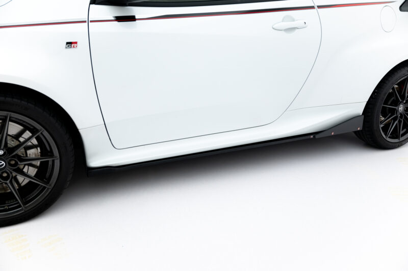 White car side panel with door handle, red side stripe, and black alloy wheel in foreground
