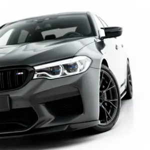 Front-left view of a gray BMW M5 with a prominent kidney grille and '#MAXTONIZED' plate on a white background