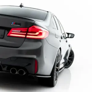Rear view of a gray BMW M competition with illuminated taillights and a '#MAXTONIZED' plate.