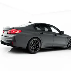 Dark gray BMW M4 coupe shown from the rear three-quarter angle in a white studio setting, highlighting taillights and aftermarket wheels.