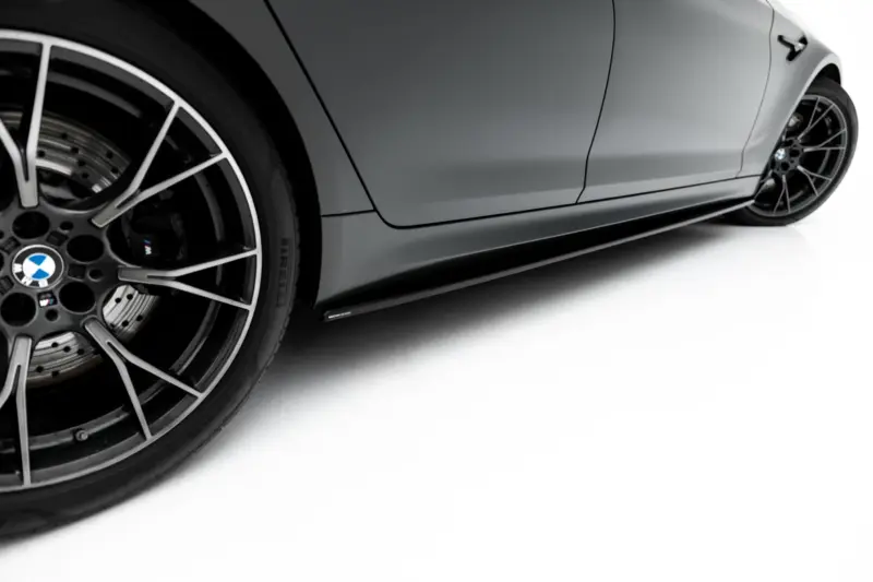 pol_po_Set-of-Splitters-V-1-BMW-M5-F90-23925_8webp - OPSHOLDERS Close-up of a silver BMW sports car showing a large multi-spoke alloy wheel, brake disc, and gray body panel with the M badge visible on the brake caliper area.