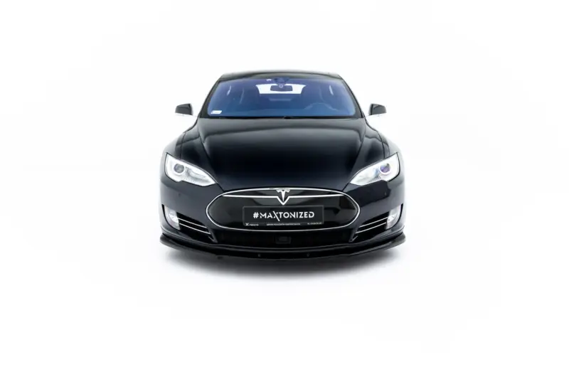 Front view of a black Tesla car facing the camera, with '#MAXTONIZED' on the license plate area and prominent headlights.