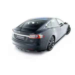 Rear three-quarter view of a dark gray Tesla Model S parked on a white studio background shows the taillights and curved roofline clearly visible.