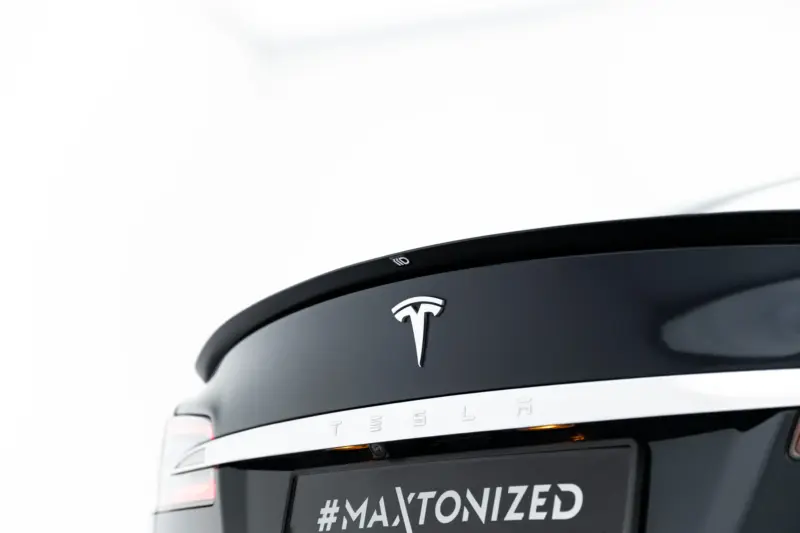 Rear of a white Tesla SUV showing the chrome Tesla emblem and the hashtag #MAXTONIZED on the license plate area.