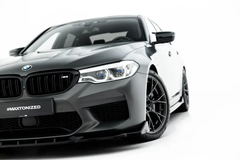 pol_po_Set-of-Splitters-V-2-BMW-M5-F90-23926_11webp - OPSHOLDERS Front-left angle of a dark gray BMW M5, showing the grille, headlight, and front wheel with a #MAXTONIZED plate tag visible on the bumper.