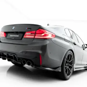 Rear three-quarter view of a gray BMW M5 Competition with a #MAXTONIZED plate on the trunk.