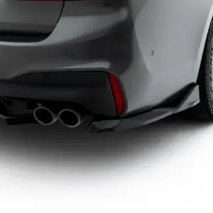 Close-up of the rear left side of a dark gray sports car, featuring quad exhaust tips and a sculpted bumper.