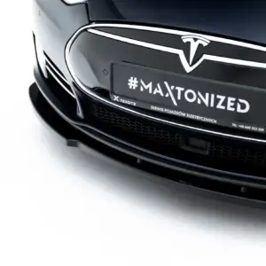 Close-up of the front of a black Tesla car, showing a plate with the text '#MAXTONIZED'.