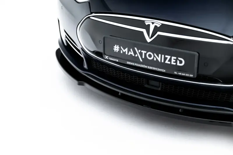 Close-up of the front of a black Tesla car, showing a plate with the text '#MAXTONIZED'.