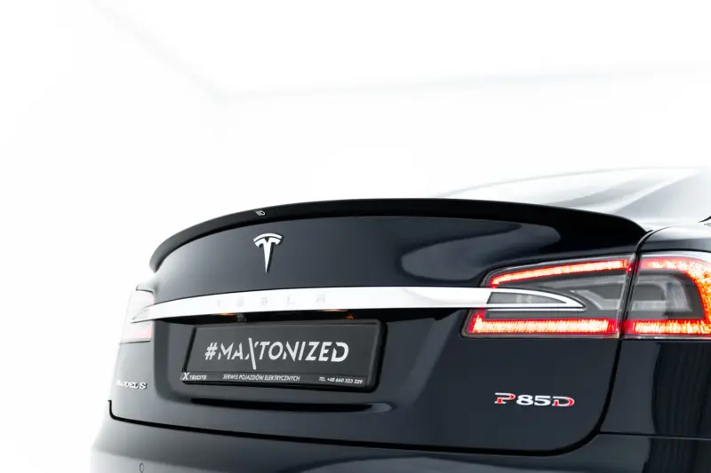 Rear view of a dark Tesla Model S with the Tesla logo, chrome trim, and red taillights visible; a license-area reads #MAXTONIZED