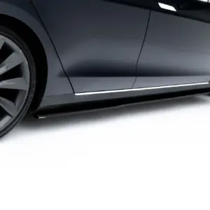 Close-up of a dark gray Tesla side panel with a large alloy wheel visible at the left.