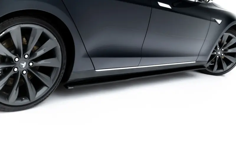 Close-up of a dark gray Tesla side panel with a large alloy wheel visible at the left.