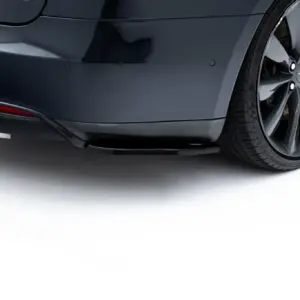 Close-up of a dark gray car's rear bumper and right rear wheel with a multi-spoke alloy rim visible.