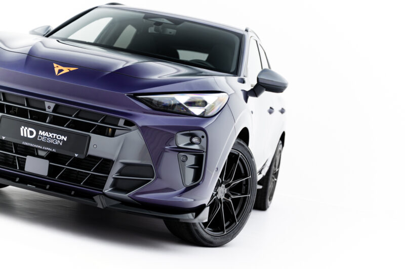 Close-up of the front-left of a purple SUV, showing the headlight, grille, and orange emblem on the hood.