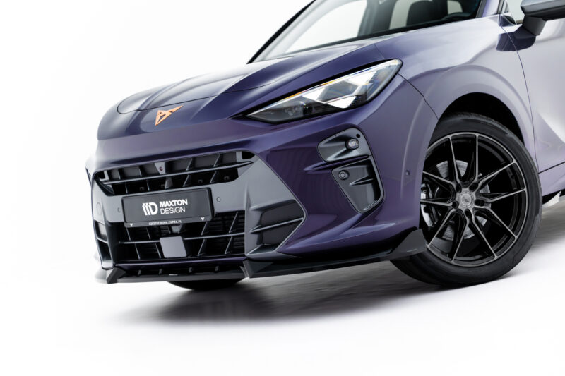 Close-up of a purple sports car front end, showing the headlight, grille, and alloy wheel.