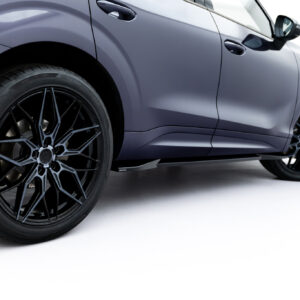 Close-up side view of a gray car highlighting a large black alloy wheel and tire near the front fender.