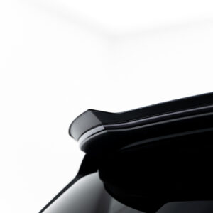 Close-up of a glossy black car body with chrome trim against a white background.