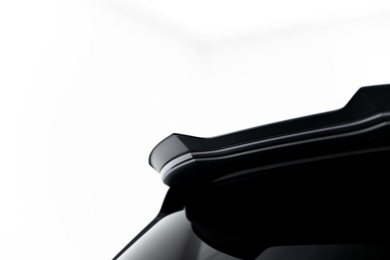 Close-up of a glossy black car body with chrome trim against a white background.