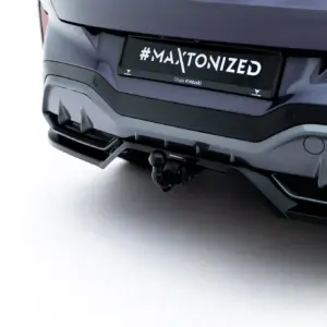 Close-up of a car's rear bumper with a license plate reading '#MAXTONIZED' and a tow hitch underneath.