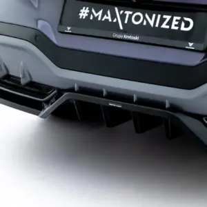 Close-up of a car's rear bumper and license plate displaying '#MAXTONIZED' with branding text underneath (Grupa Krotoski).