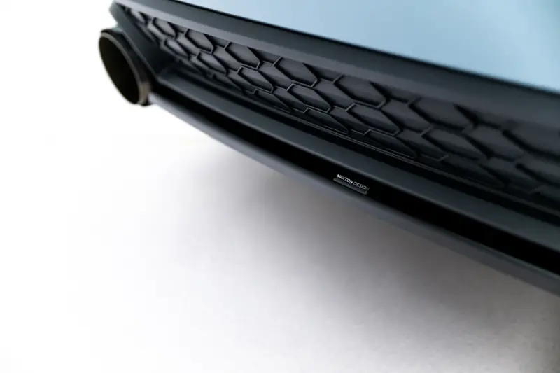 Close-up of a blue car's front grille with a hexagonal mesh and a Maxton Design badge visible on the lower edge.
