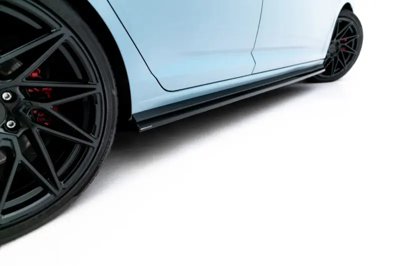 Close-up of a blue car's side with a large black alloy wheel and red brake calipers visible at the edge of the frame.