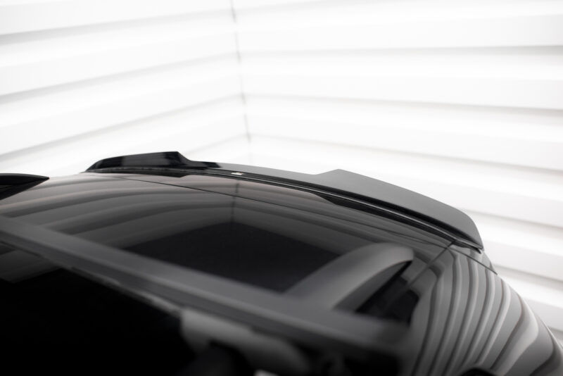 Close-up of a dark car roof and rear window with reflections, set against a bright, blurred backdrop of horizontal blinds